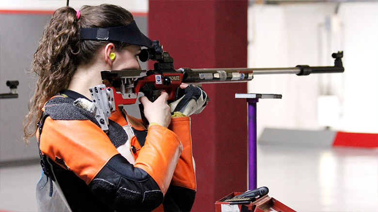 Young collegiate shooting competitor at an indoor range.