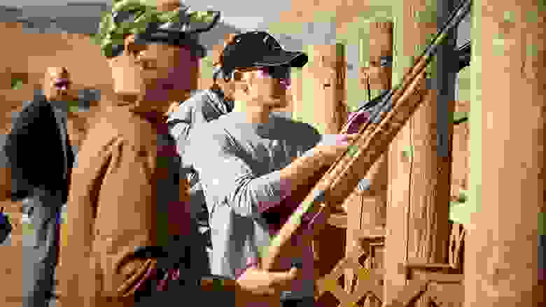Several men in ball caps shooting shotguns at an outdoor range.