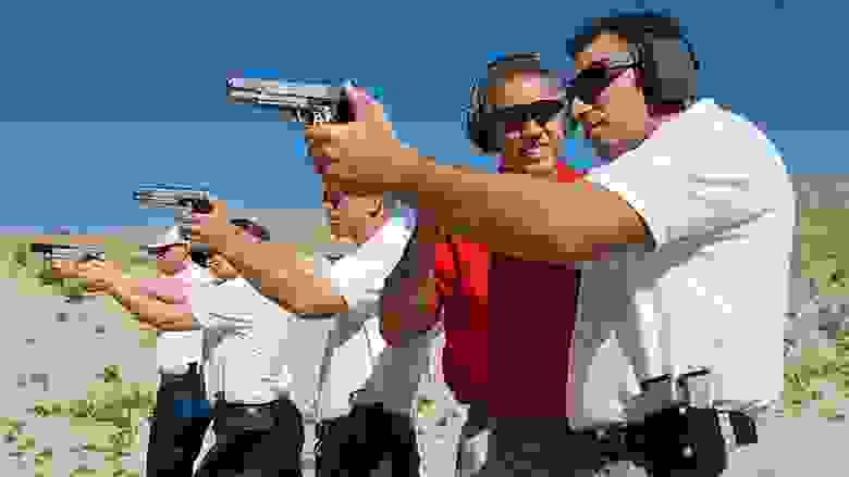 NRA Instructor Working with People in a Firing Line at an Outdoor Gun Range in the Desert