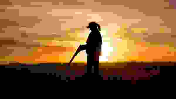 Sunset Silhouette of a Female Hunter Reloading Her Shotgun