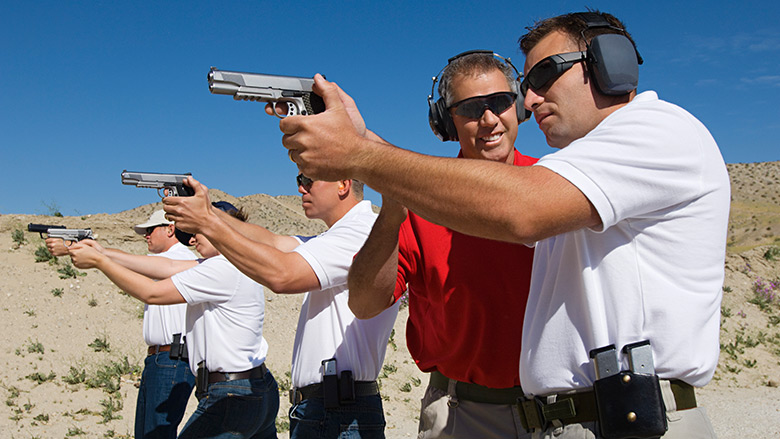 NRA Instructor Working with People in a Firing Line at an Outdoor Gun Range in the Desert