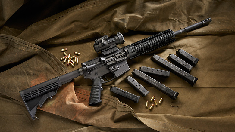 Black Sporting Rifle and various Magazines and Ammo Laying on a Canvas Drop