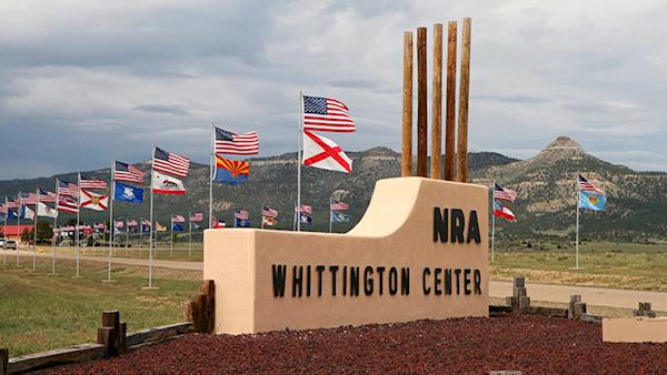 Entrance Way to the NRA Whittington Center with Flags and Mountains in the Background